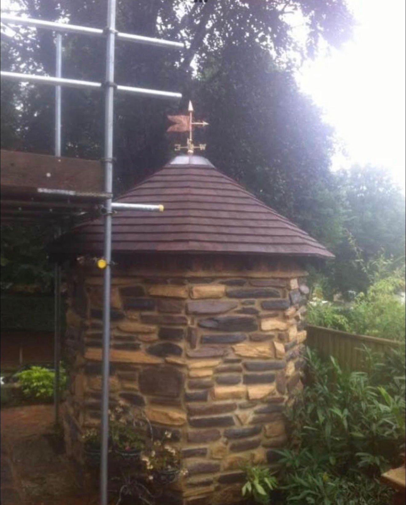 Completed cedar-shingled garden turret with copper weathervane